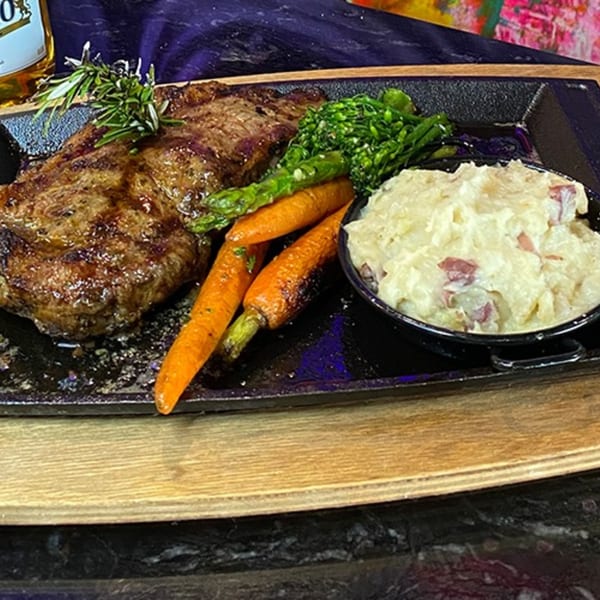 Grilled steak with rosemary, roasted carrots, asparagus, and a side of mashed potatoes.