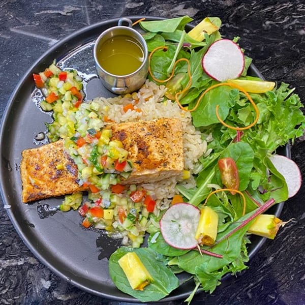 Grilled salmon with rice, colorful salsa, and a fresh green salad with radishes and pineapple.