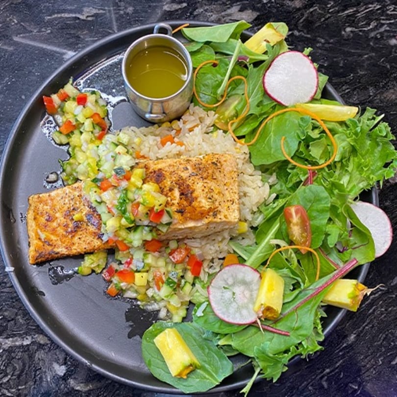 Grilled salmon with rice, colorful salsa, and a fresh green salad with radishes and pineapple.