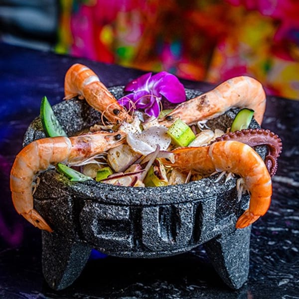 Culichis Urban Kitchen's molcajete with shrimp, octopus, avocado, and red onion, garnished with an orchid.