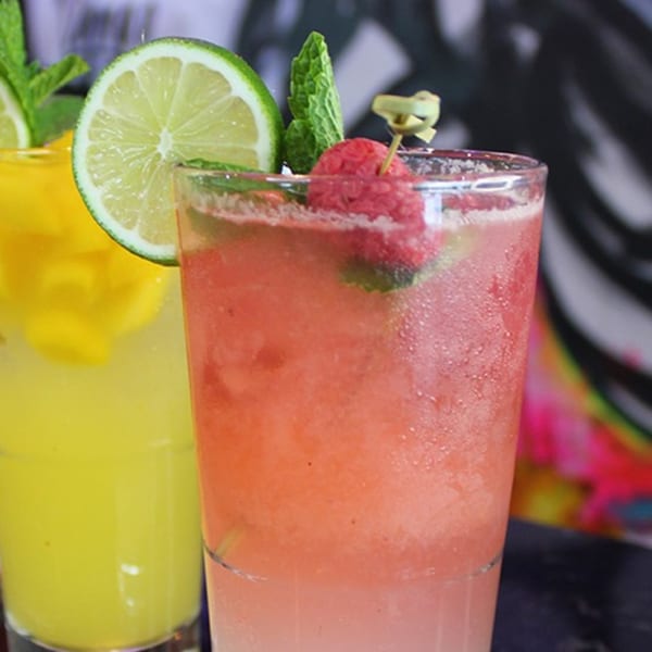 Two vibrant drinks, one yellow with lime, one pink with raspberry and mint, from Culichis Urban Kitchen.